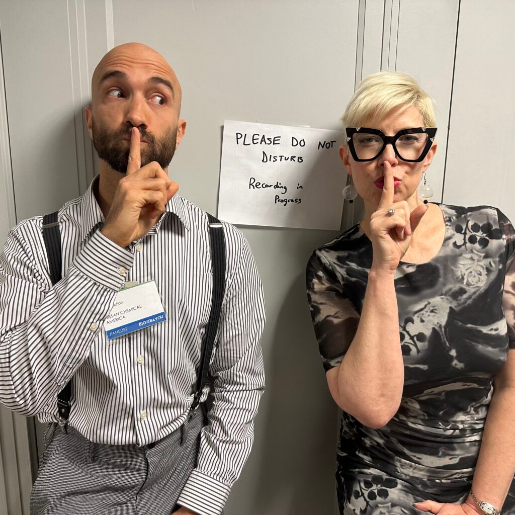 Aziz Abadsafian and Elaine Hamm making a shushing motion in front of a sign saying, "Please do not disturb, recording in progress."